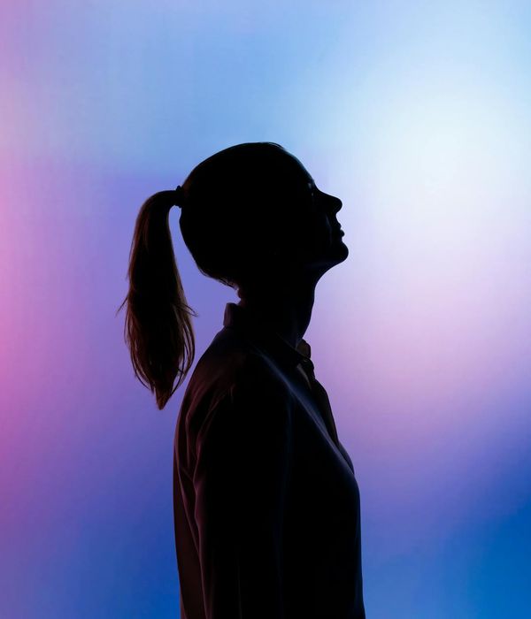 Silhouette of a person in a yoga warrior pose against a soft background.